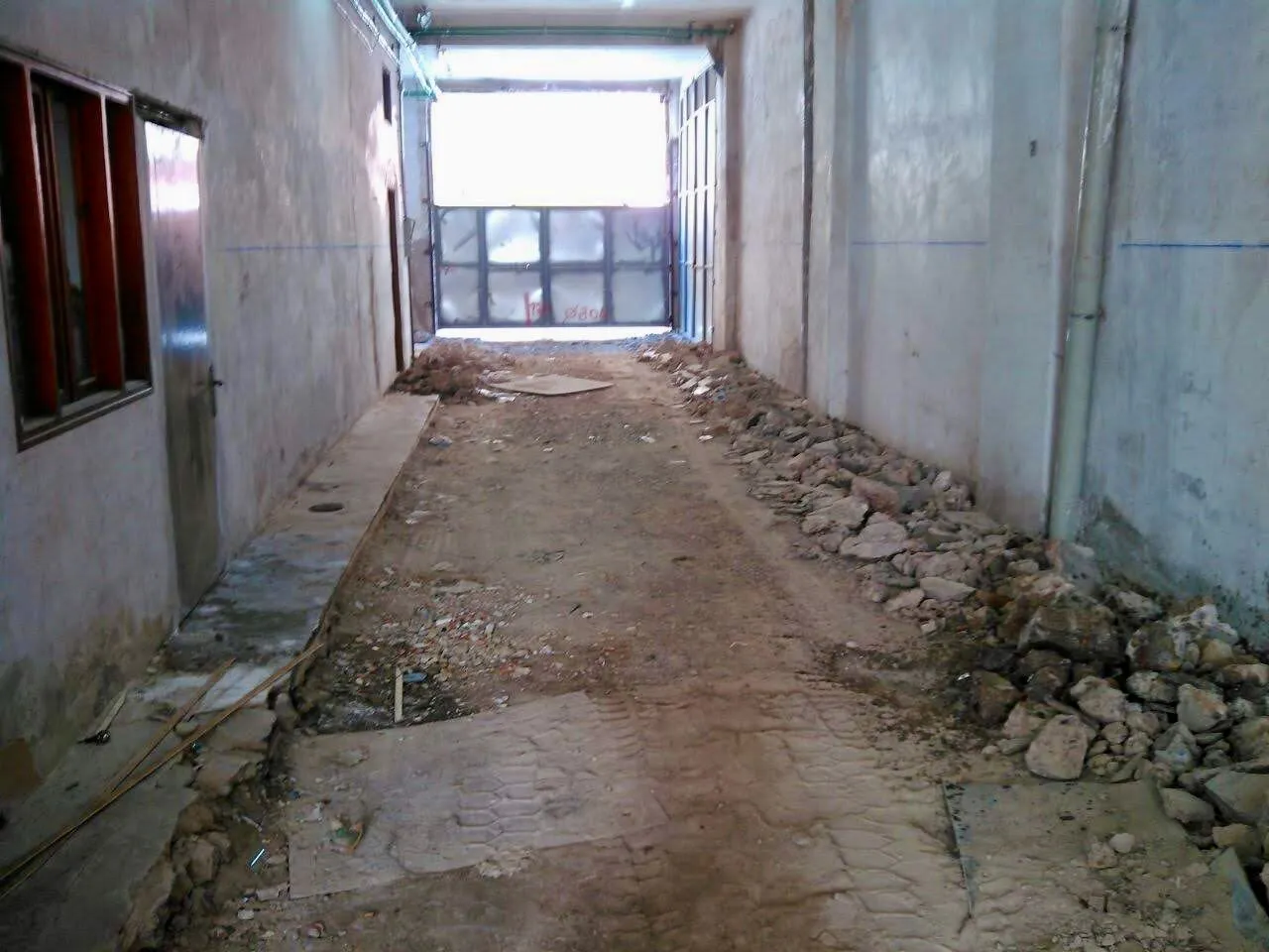 El corredor de acceso al patio de manzana: 3,20 × 3,65 m y 30 m de longitud — el único paso para equipos, armaduras y hormigón